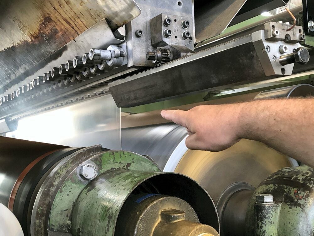 Mit einer Temperatur von 330 Grad kommt der Kunststofffilm aus dem Extruder. Gleich wird er auf Papier gepresst.