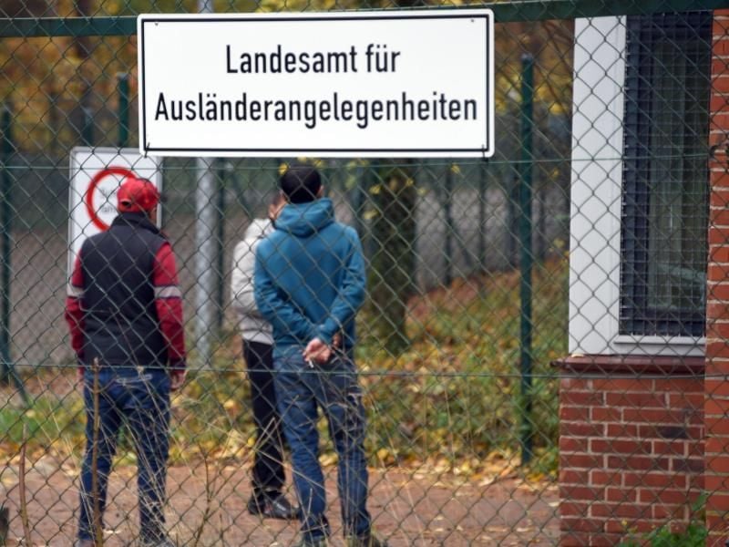 Junge Männer sind durch einen Zaun vor dem Eingang der Erstaufnahmeeinrichtung zu sehen. Foto: Carsten Rehder/Archiv