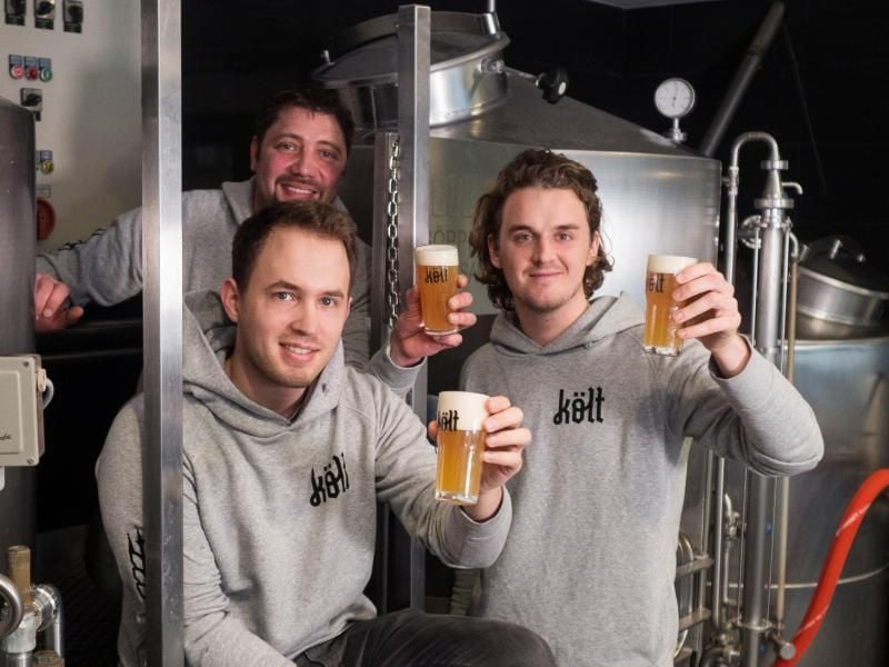 Die Jung-Unternehmer Matthias Ross (l-r), Henning Barkey (hinten) und Hans Berlin haben den Versuch gestartet, die alte Rivalität zu überbrücken. Sie probieren es mit Bier, gebraut genau zwischen den beiden Rhein-Metropolen. Foto: Költ Bier