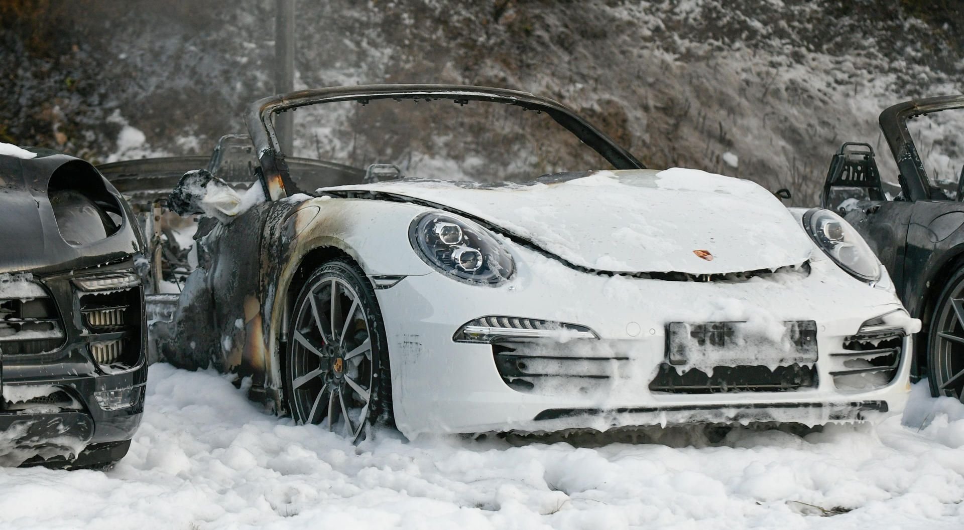 Ausgebrannte Fahrzeuge der Firma Porsche auf dem Parkplatz des Hamburger Porsche-Zentrums im Löschschaum der Feuerwehr.