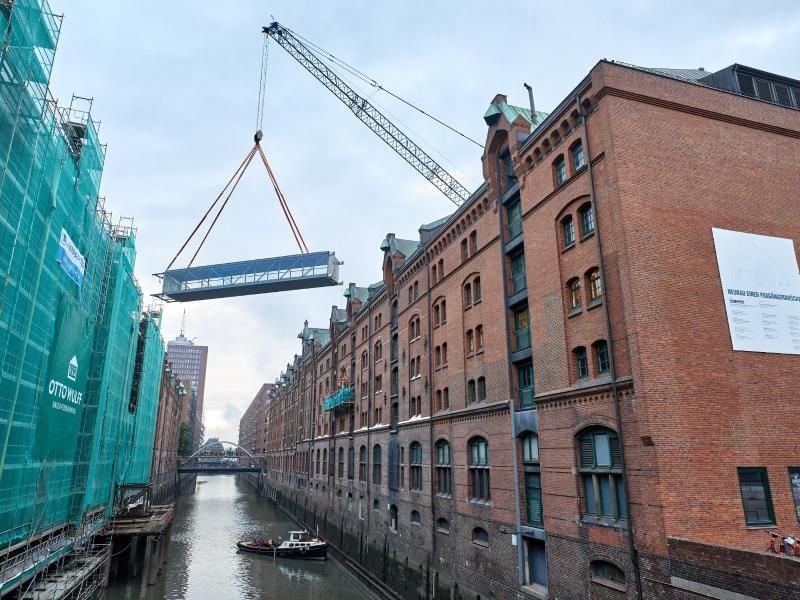 Eine Brücke schwebt an einem Kran über dem Kehrwiederfleet. Foto: Georg Wendt/dpa