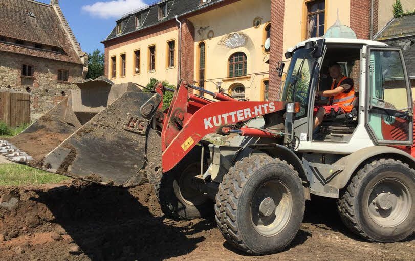 Ein Radlader kippt die Erde vor dem Gutshaus ab.