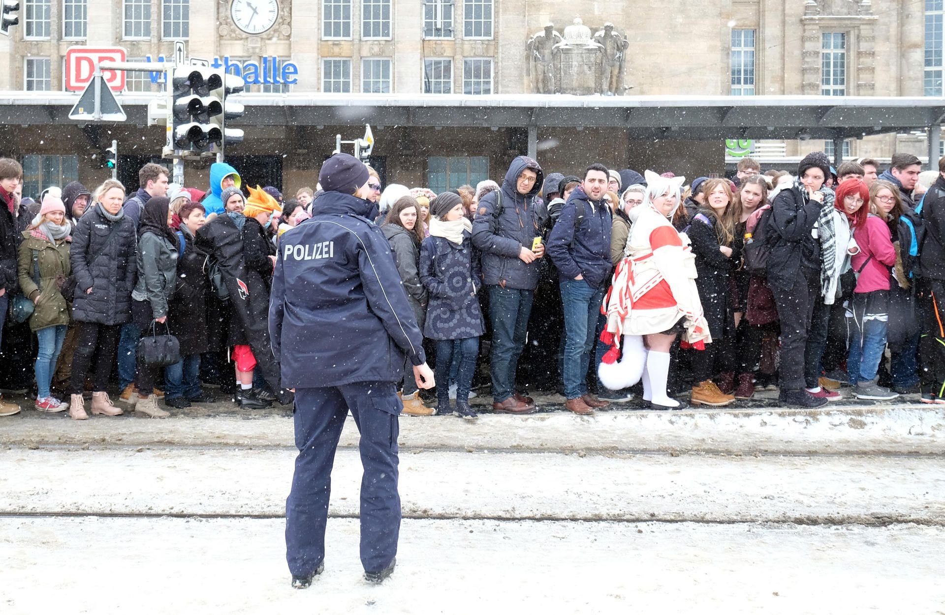 Schneechaos in Leipzig: Fahrgäste, darunter Besucher der Buchmesse, stehen dicht gedrängt an einer Haltestelle der Straßenbahn vor dem Hauptbahnhof. Eine Polizistin versucht den Andrang zu regeln.