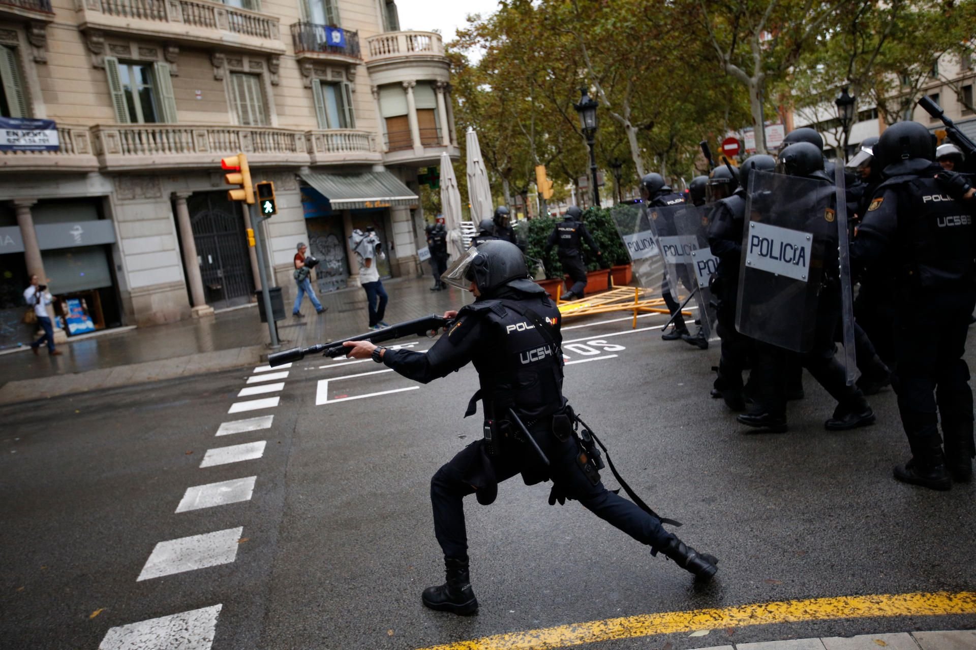 Ein spanischer Nationalpolizist schießt mit Gummigeschossen in Barcelona auf Menschen, die ein von der katalanischen Regierung bestimmtes Wahllokal in einer Schule erreichten wollen.