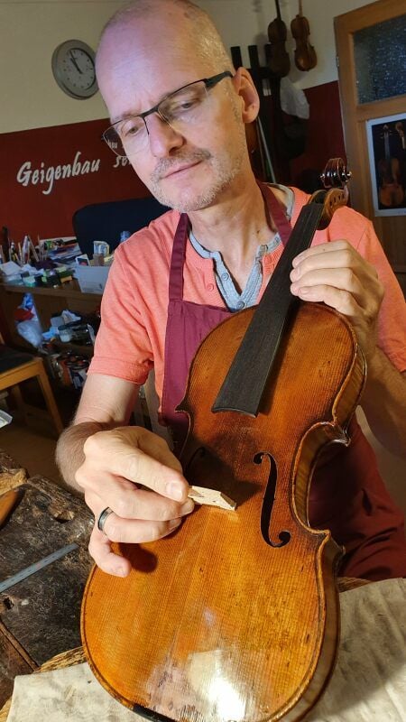 Geigenbaumeister Matthias Vorbrodt passt den neuen Steg an.