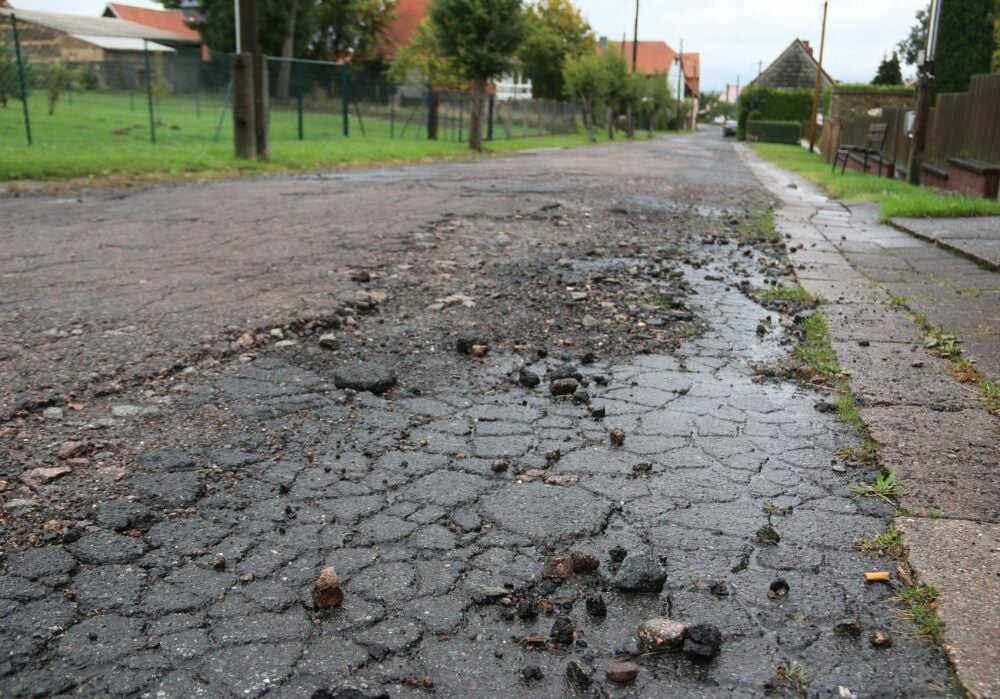 So sieht die Rotdornstraße am Dorfgemeinschaftshaus aus. 2023 soll sie endlich grundhaft saniert werden. Teilnehmer des Stadtgesprächs mahnten bis dahin zumindest Reparaturen an.