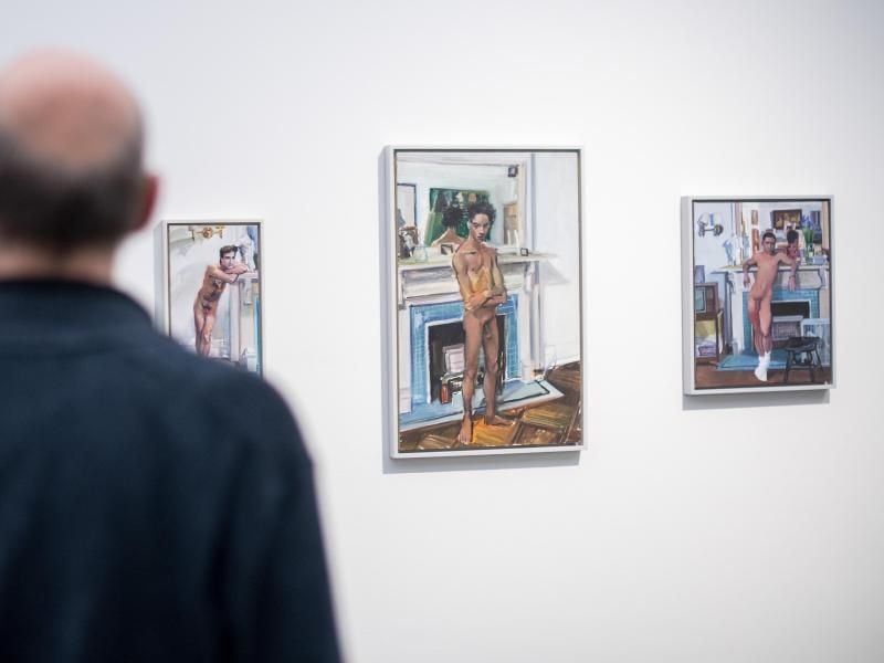 Ein Besucher vor einer Reihe von kleinen Männerporträts. Foto: Sebastian Gollnow