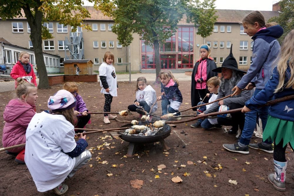 Die Hortkinder der Grundschule „Max Lingner“ drängen sich um die Feuerschale, damit sie schnellstmöglich ihren Knüppelkuchen genießen können. Kulinarisch hat die Halloween-Party einiges zu bieten.
