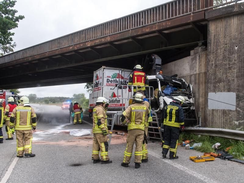 Feuerwehrmänner arbeiten an einem LKW, der eine Eisenbahnbrücke gerammt hat. Foto: Benjamin Nolte