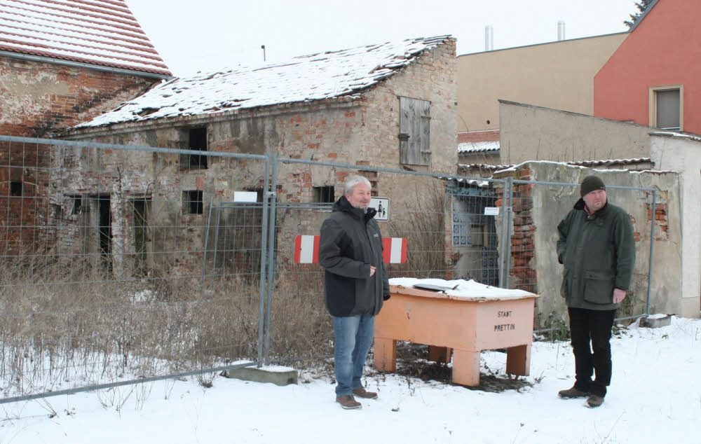 Rolf Häuser (links), Leiter des Bauordnungsamtes beim Landkreis Wittenberg, und Pressesprecher Ronald Gauert am Prettiner Grundstück Elbstraße 16. Das verfallene Wohnhaus ließ der Kreis 2016 aus Sicherheitsgründen abreißen, Teile vom Nebengelass stehen, durch einen Bauzaun gesichert, noch.