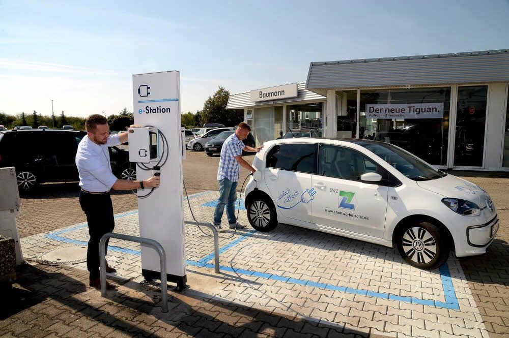 Gilbert Baumann und Sebastian Nicolai nutzen die Ladestation für Elektrofahrzeuge.