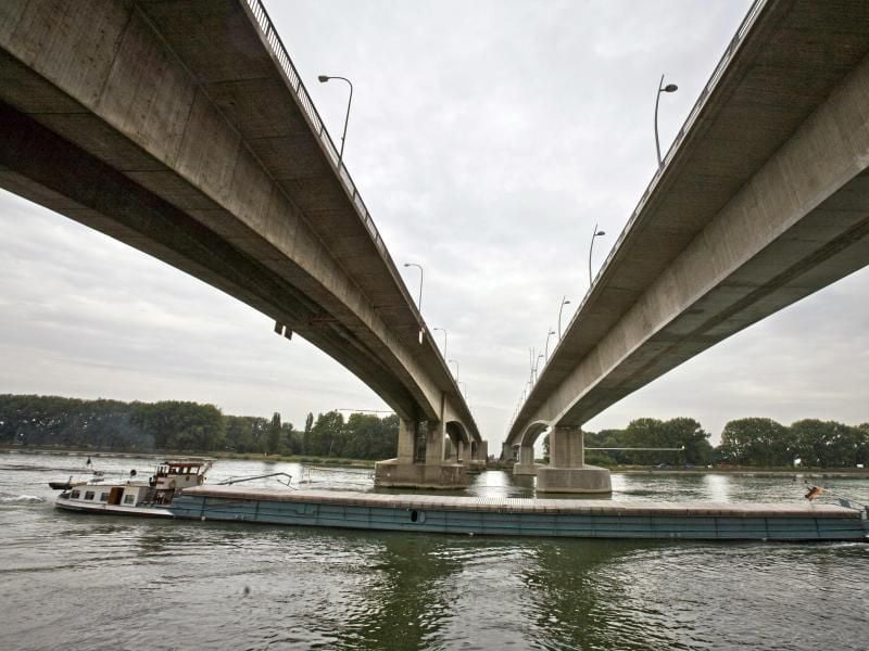 Ein Schiff fährt bei Worms unter der alten Nibelungenbrücke (l) und der neuen Rheinbrücke (r) hindurch. Foto: Frank Rumpenhorst dpa/Archiv