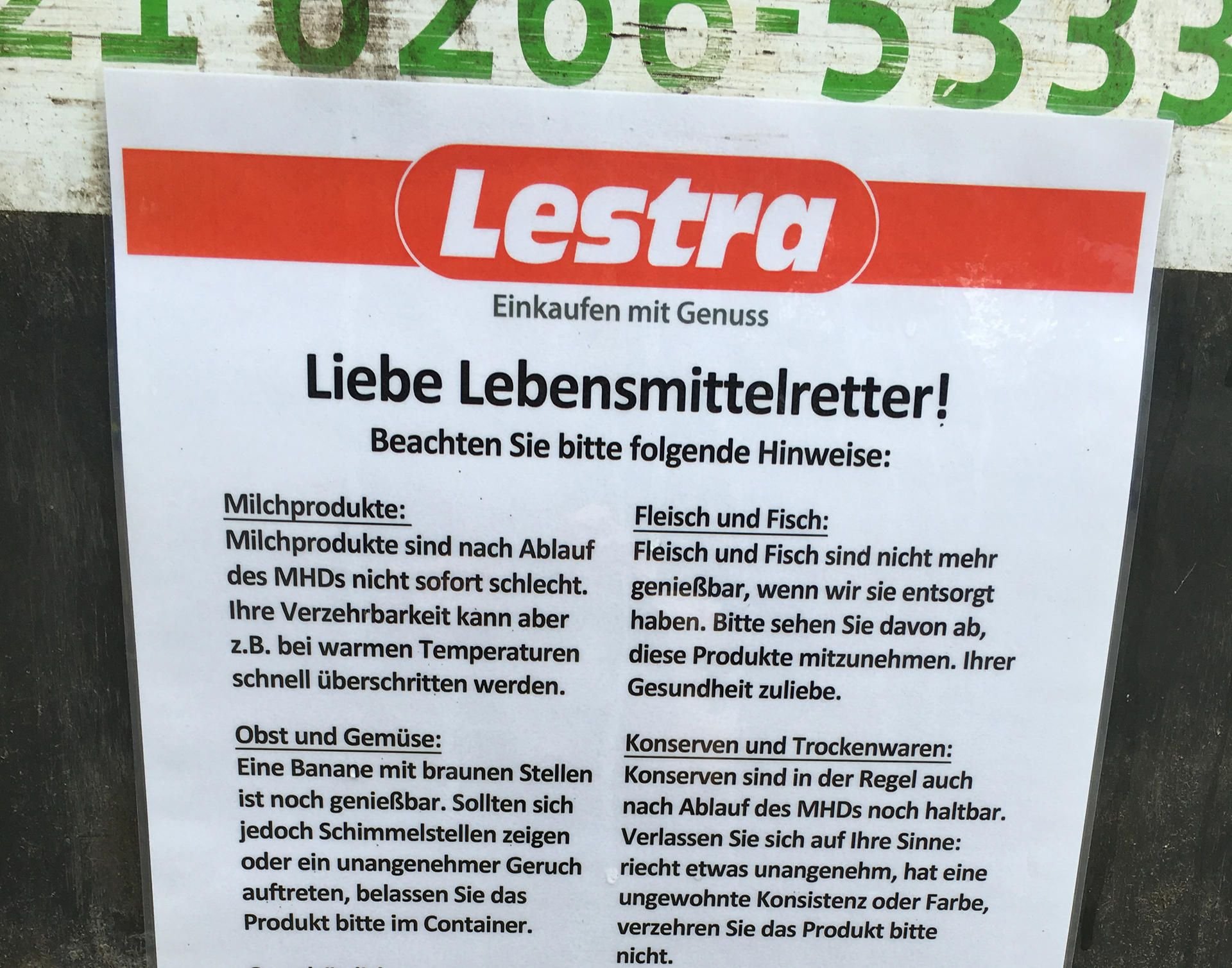 Ein Schild mit Hinweisen hängt zum sogenannten Containern an einem Müllcontainer am Kaufhaus Lestra.