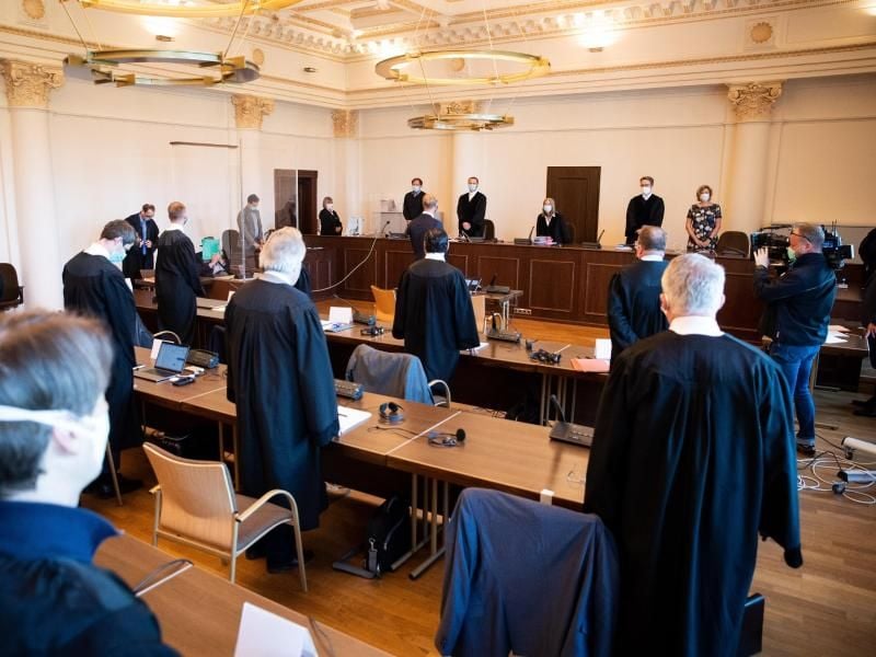 Anne Meier-Göring (hinten, 3.v.r), Vorsitzende Richterin, und weitere Prozessteilnehmer stehen zu Beginn eines weiteren Prozesstages gegen einen 93 Jahre alte ehemaligen SS-Wachmann im Konzentrationslager Stutthof im Sitzungssaal des Landgerichts. Foto: Christian Charisius/dpa/Pool/dpa