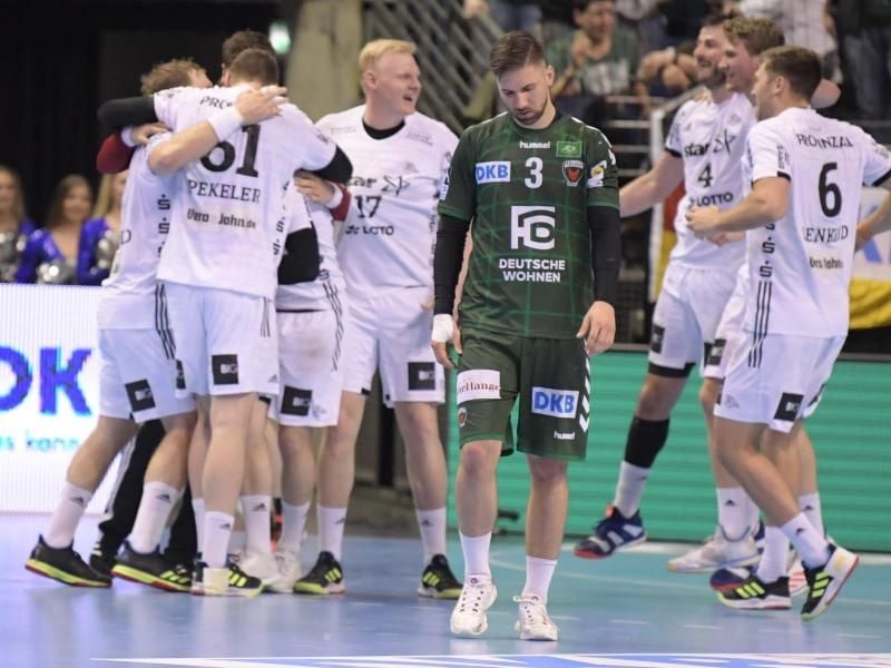Die Mannschaft vom THW Kiel jubelt über den Sieg, während Fabian Wiede von den Füchsen enttäuscht den Platz verlässt. Foto: Jörg Carstensen