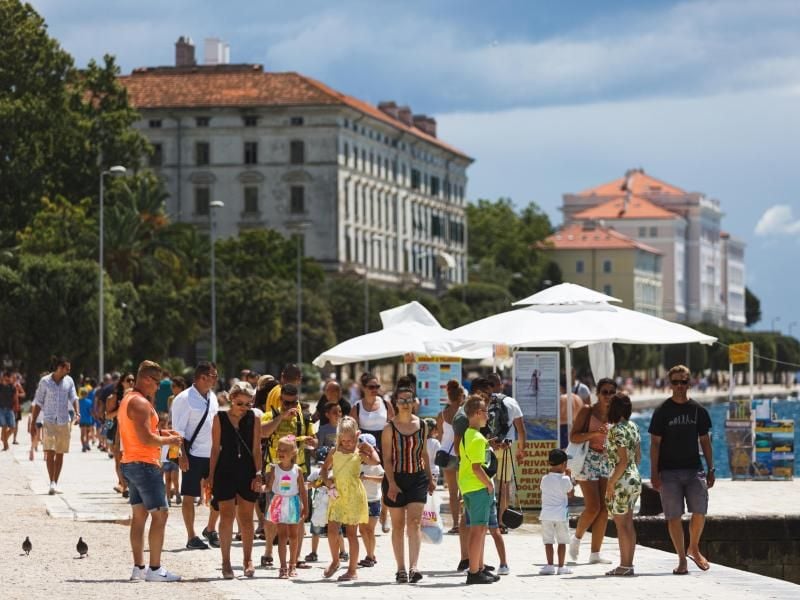 Touristen spazieren an der Uferpromenade in Zadar, Kroatien entlang. Die kroatische Tourismusbranche fürchtet eine weitreichende Reisewarnung der Bundesregierung. Foto: Marko Dimic/Pixsell/Xinhua/dpa