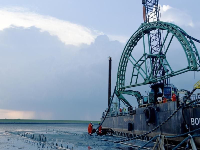 Das Endstück eines 516 Kilometer langen Seekabels wird vom Kabelverlegeschiff „Boka Connector” im Watt unter dem Deich hindurch an Land gezogen. Foto: Carsten Rehder