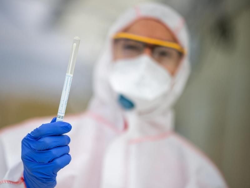 Ein Mitarbeiter hält in einem Abstrichzentrum einen Corona-Testabstrich in der Hand. Foto: Sebastian Gollnow/dpa/Symbolbild
