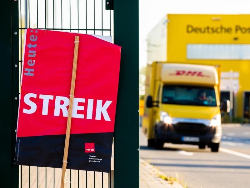 Ein Schild der Gewerkschaft Verdi mit der Aufschrift "Heute Streik" steht vor einer Deutsche-Post-DHL-Niederlassung. Foto: Moritz Frankenberg/dpa