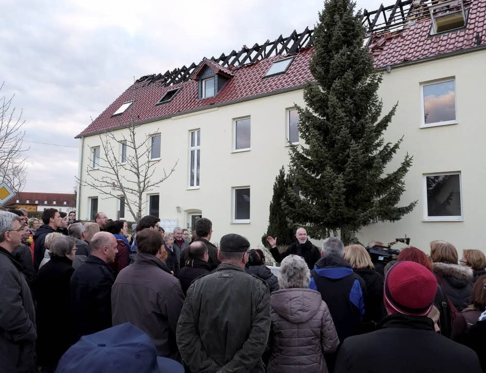 Nach der Brandnacht fanden in Tröglitz Friedensgebete statt. Dabei zog es Teilnehmer auch vor das Haus mit dem ausgebrannten Dachstuhl.