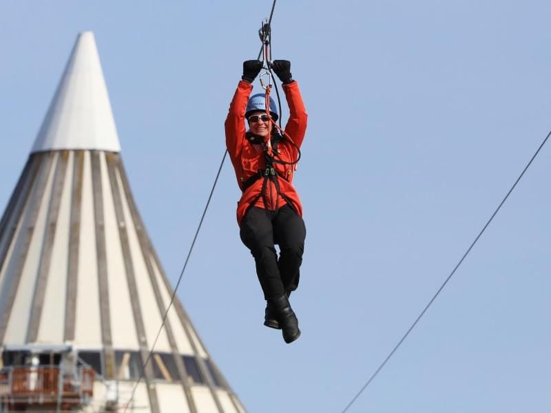 Eine Frau testet die neue 450 Meter lange Zipline vom Jahrtausendturm im Elbauenpark. Foto: Peter Gercke