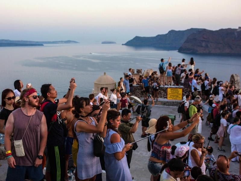 Touristen fotografieren den Sonnenuntergang. Foto: Angelos Tzortzinis/Illustration