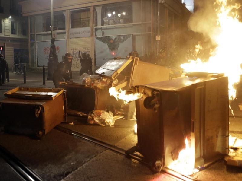 Polizisten stehen in Marseille neben brennenden Mülltonnen, die von Olympique-Fans nach dem verlorenen Europa-League-Finale gegen Atlético Madrid in Brand gesetzt wurden. Foto: Claude Paris/AP