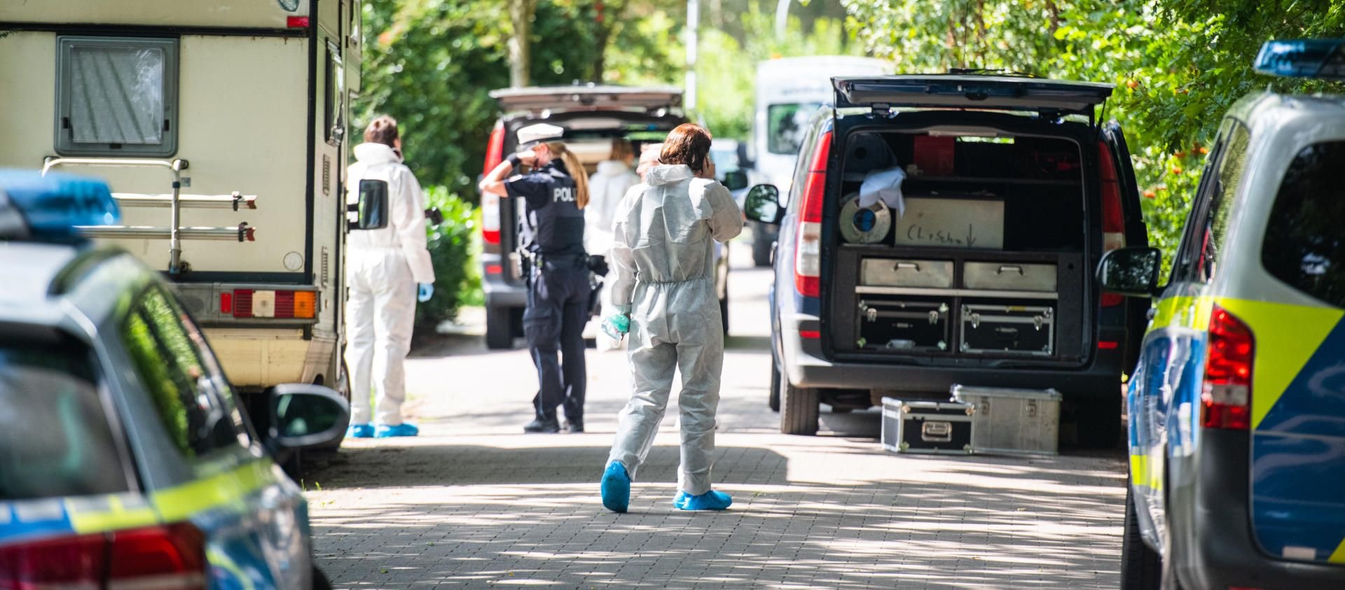 Polizisten und Beamte der Spurensicherung stehen vor dem Wohnhaus in Tornesch, in dem die Leiche einer Frau gefunden wurde.