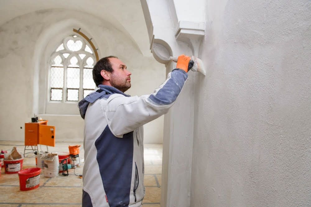 Maler Martin Schönburg streicht die Wände des künftigen Besucherempfangs mit einer kalkhaltigen Farbe. An der Decke des Raumes kommt Leinfarbe zum Einsatz.
