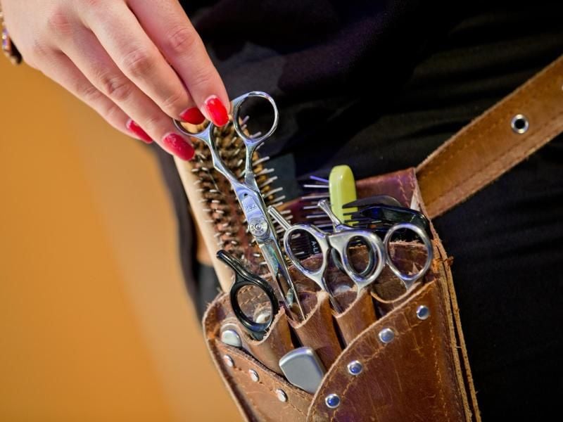 Das Handwerkszeug eines Friseurs steckt in der Gürteltasche einer Friseurin. Foto: Daniel Karmann/Archivbild