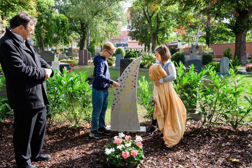 Klinikseelsorger Jürgen Pillwitz sowie Klara Menzel und Eric Zier weihen die Grabstelle für Sternenkinder auf dem Naumburger Othmarsfriedhof ein.
