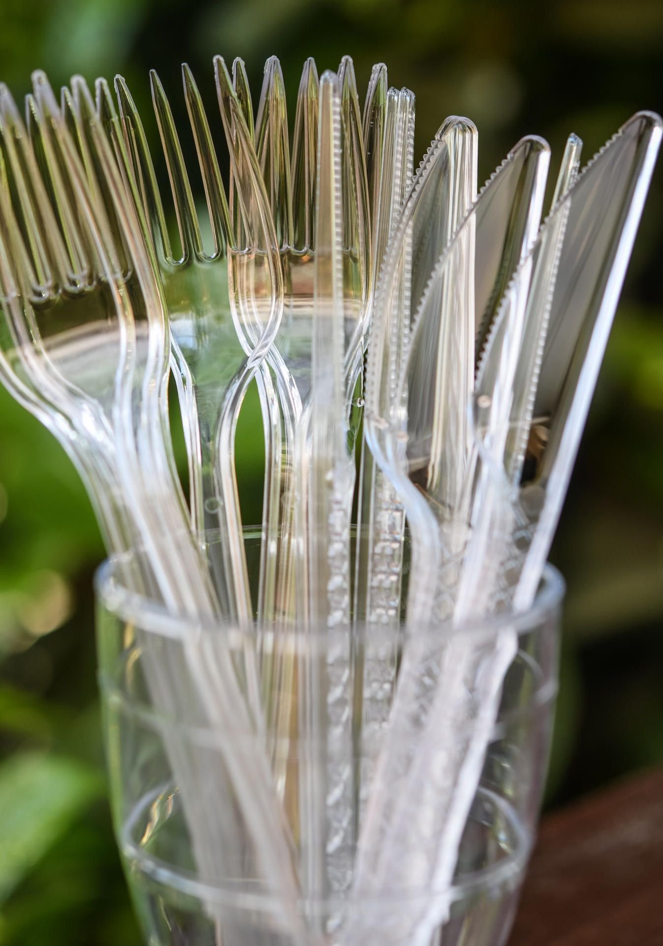 Einwegbesteck - Messer und Gabeln aus Plastik - stehen in einem Kunststoffbecher. (Symbolbild)