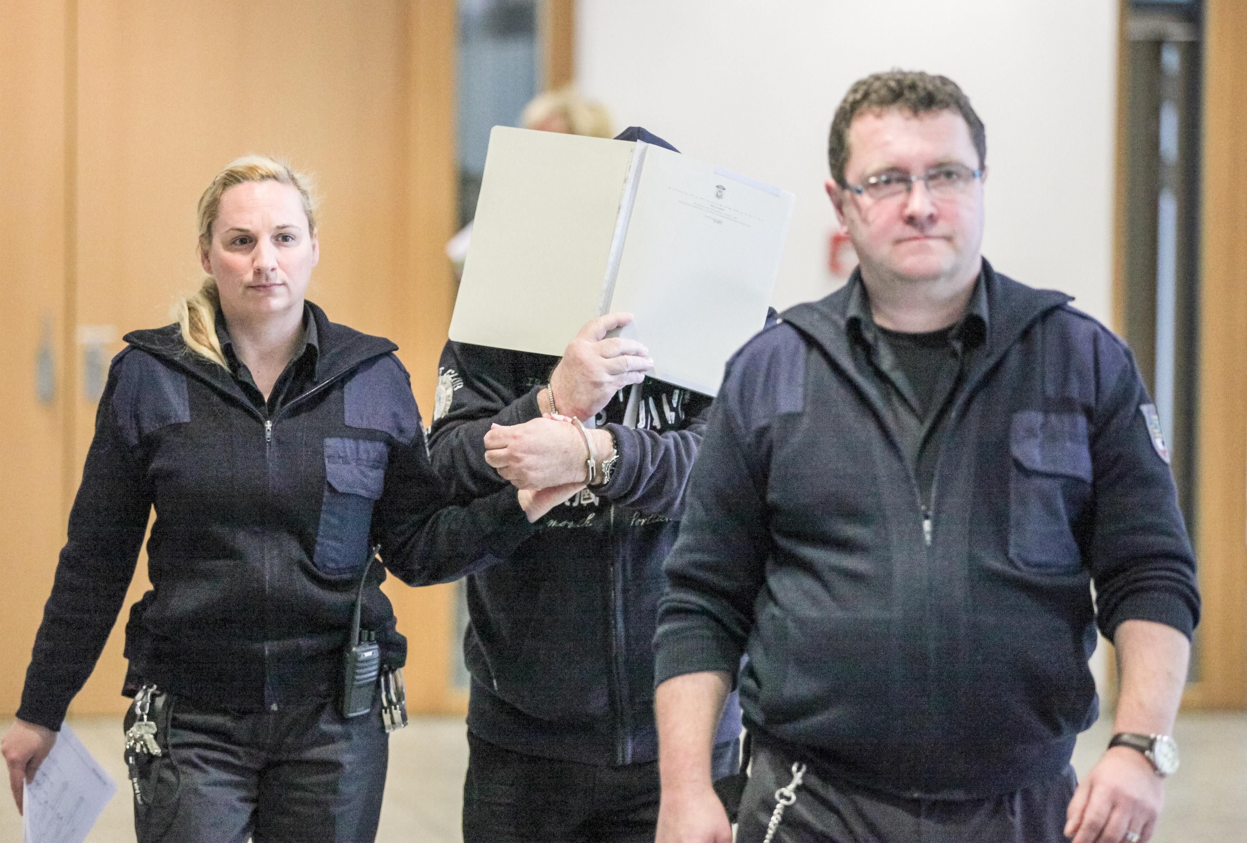 Der Angeklagte Heinz-Dieter D. (M.) wird von zwei Justizvollzugsbeamten in den Verhandlungssaal geführt.