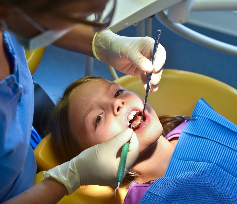 Alles in Ordnung? Ein Zahnarzt kontrolliert die Zähne eines Mädchens. Die Vorsorgeuntersuchungen bei Kindern sind für die Gesundheitsämter verpflichtend.