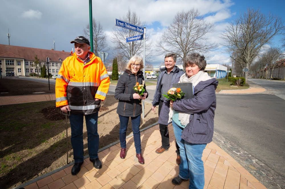 Der Friedensplatz in Tröglitz ist fertig: Ortsbürgermeister Thomas Körner (hinten) überreicht Blumen an Marlies Fritzsche und Katrin Huth (r). Links steht Lutz Schlag von der Baufirma Schlag.
