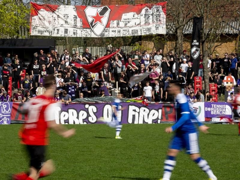 Fußballfans der Tennis Borussia Berlin (r) schauen sich mit Fans von Roter Stern Leipzig gemeinsam ein Spiel gegen den VfB Zwenkau an. Foto: Christoph Soeder/dpa