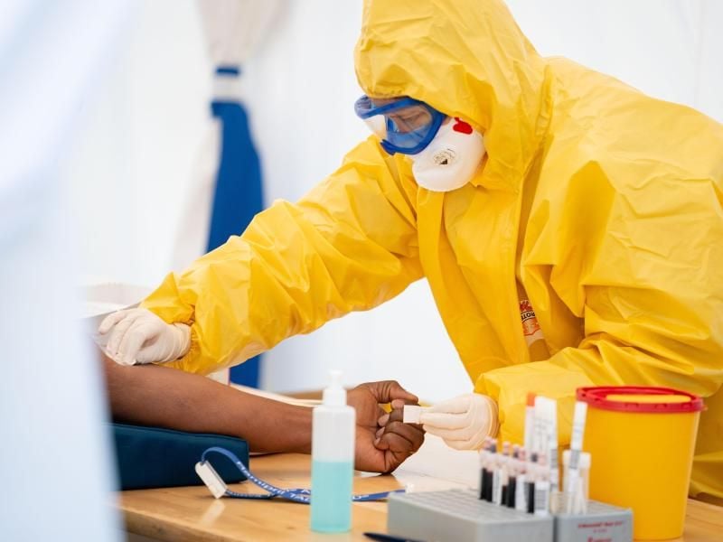 Eine Rettungssanitäterin entnimmt in einem Zelt einem Patienten Blut. Foto: Kay Nietfeld/dpa