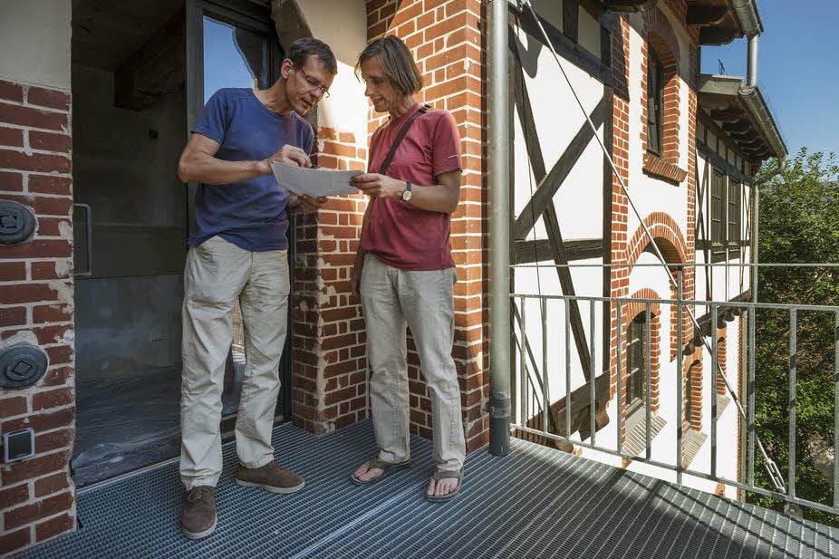 Architekt Ulrich Queck (r.) und Bauherr Carsten Dittmann studieren auf einem der Balkone, die im Hofbereich des Gebäudes entlang des ehemaligen Lastenaufzugs angebracht sind, die neuesten Baupläne.
