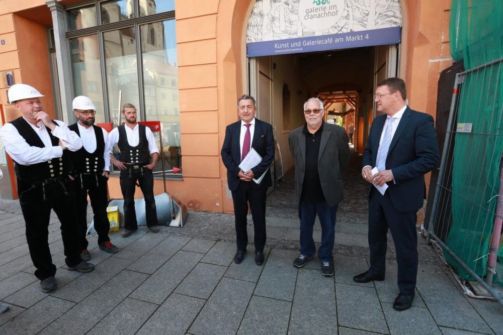 Am Wittenberger Markt: Staatssekretär Gunnar Schellenberger (Mitte) überreicht den Fördermittelbescheid an Oberbürgermeister Torsten Zugehör (rechts). Das Vorderhaus von Markt 3 schließt sich rechts des Bildes an.