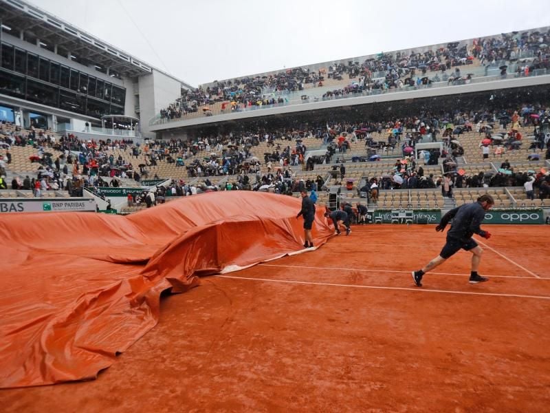 Mitarbeiter decken den Center Court ab, nachdem das Halbfinale wegen Regens unterbrochen wurde. Foto: Michel Euler/AP