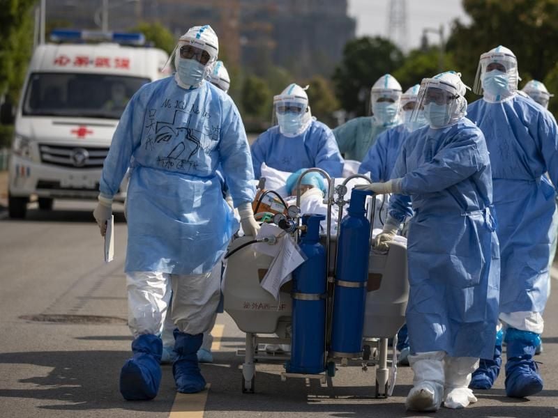 Medizinisches Personal in Schutzanzügen schiebt in Wuhan einen Covid-19-Patienten über eine Straße, um ihn in die Intensivstation zu verlegen. Foto: Shen Bohan/Xinhua/dpa