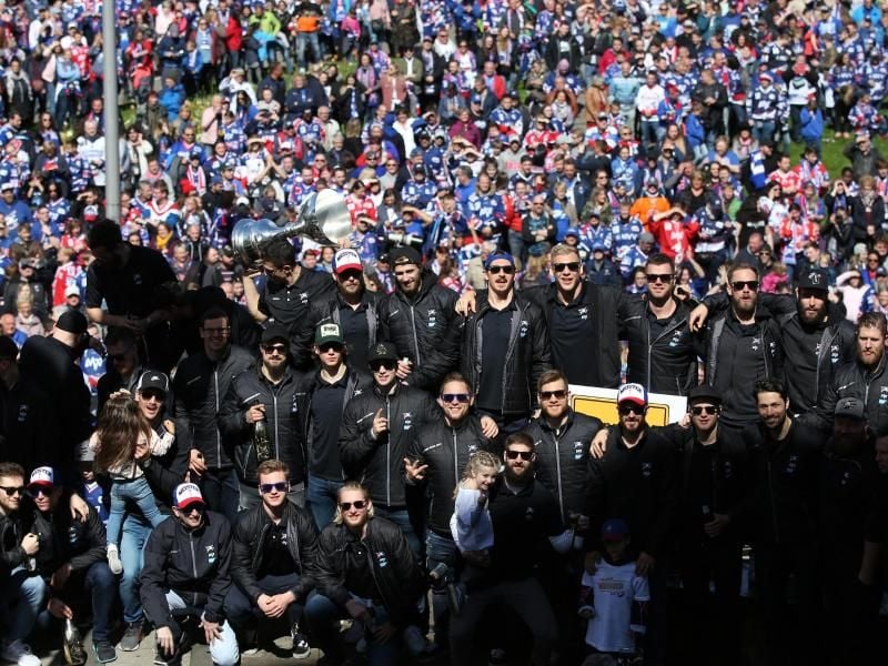 Teils mit dunklen Sonnenbrillen präsentiert die Mannschaft der Adler Mannheim den Fans den Meisterpokal. Foto: Michael Deines