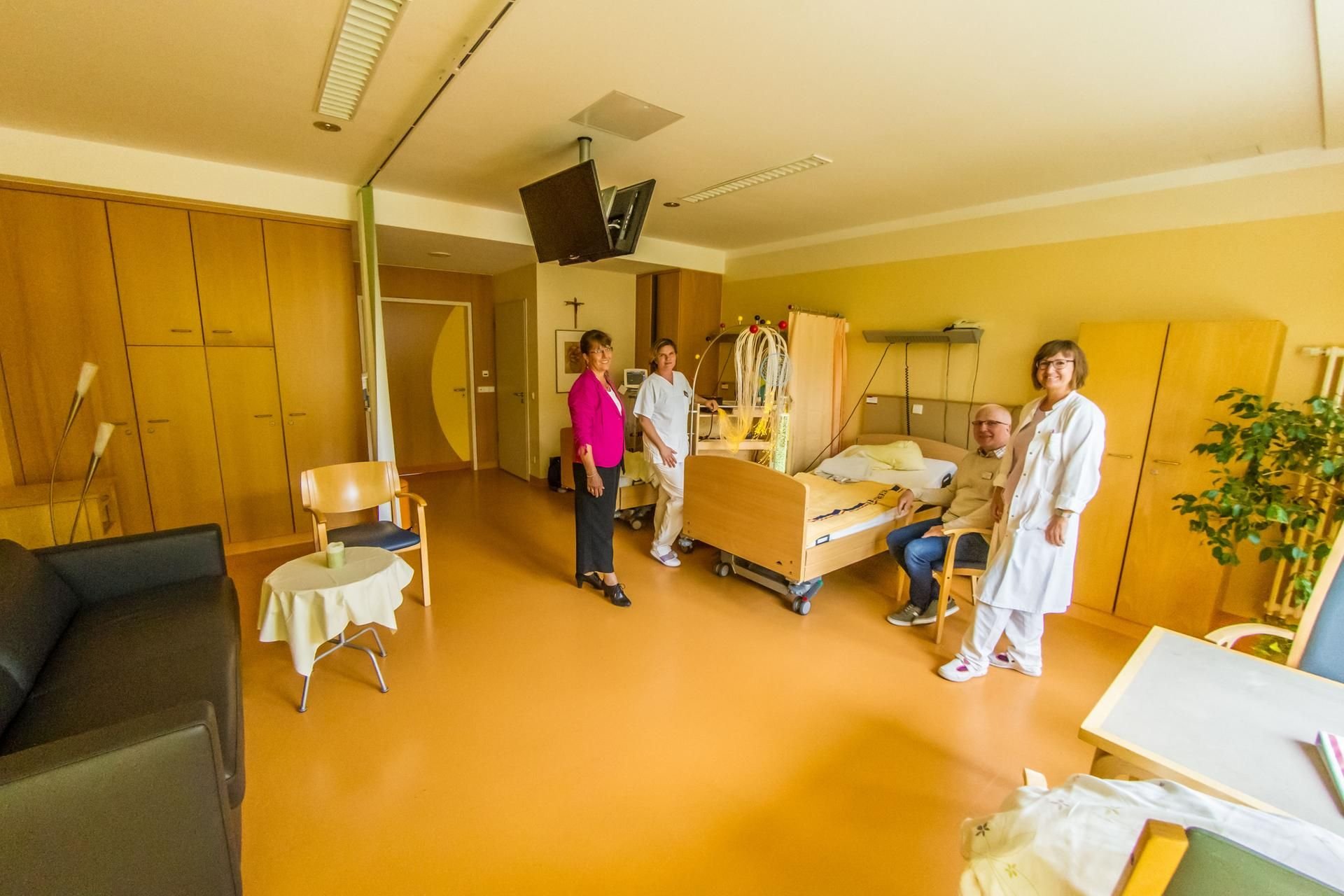 An einem der neuen Betten im neuen Palliativzimmer stehen: Geschäftsführerin Petra Stein, Schwester Katja Baierl, Seelsorger Rüdiger Kuhn, Oberärztin Tanja Thormann (v.l.). Das Sofa lässt sich ausziehen und steht Angehörigen zur Verfügung.