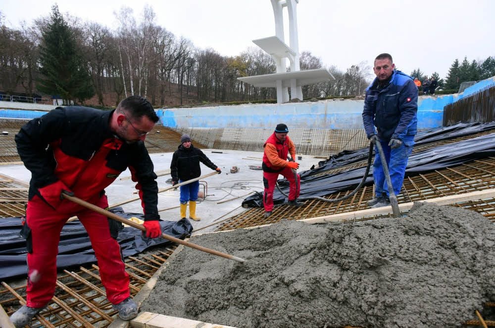 Mitarbeiter der Naumburger Bauunion bringen eine Betonschicht im Becken unterhalb des Sprungturms auf.