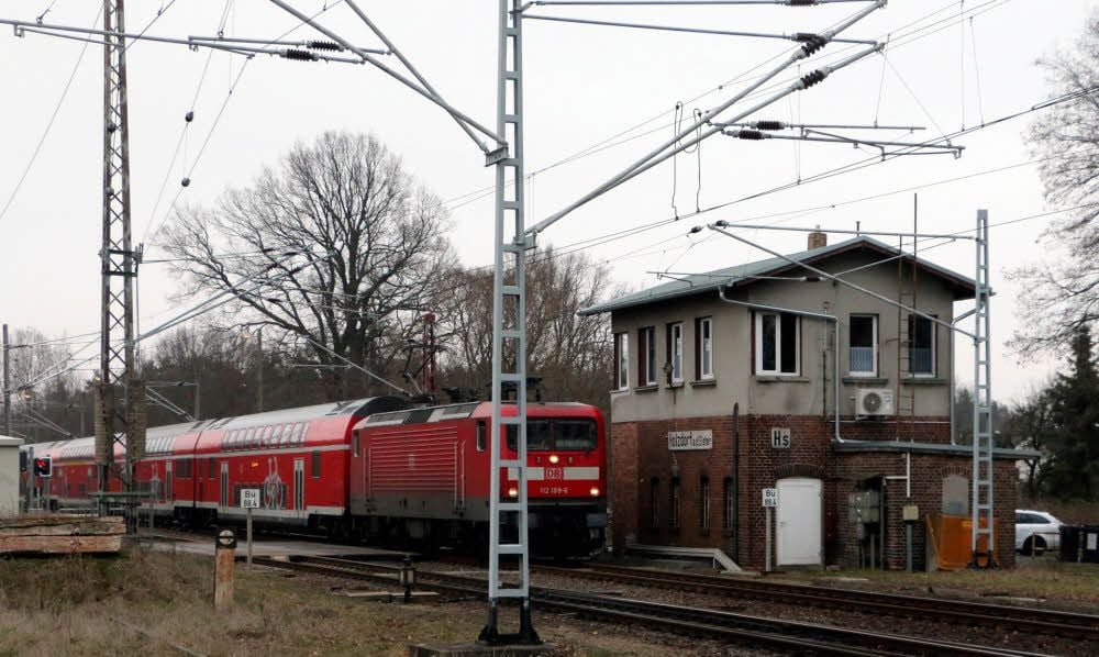 Ein Personenzug, der von Falkenberg kommt und nach Berlin fährt, passiert den Bahnübergang in Holzdorf.