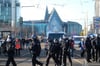 Polizisten gehen an Gegendemonstranten vorbei, die sich anlässlich der Kundgebung der Initiative ·Querdenken· auf dem Augustusplatz versammelt haben.