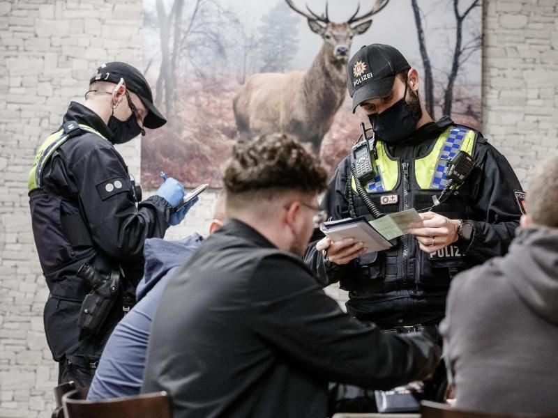 Polizisten kontrollieren in einer Hamburger Bar die Einhaltung der Corona-Vorgaben. Foto: Markus Scholz/dpa