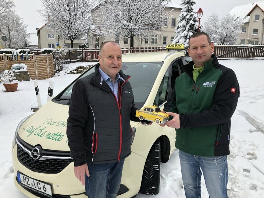 Reinhard Heinzig (links) überreicht seinem Sohn und Nachfolger an der Spitze des Familienbetriebs, Marco Heinzig, ein symbolisches Spielzeugtaxi.