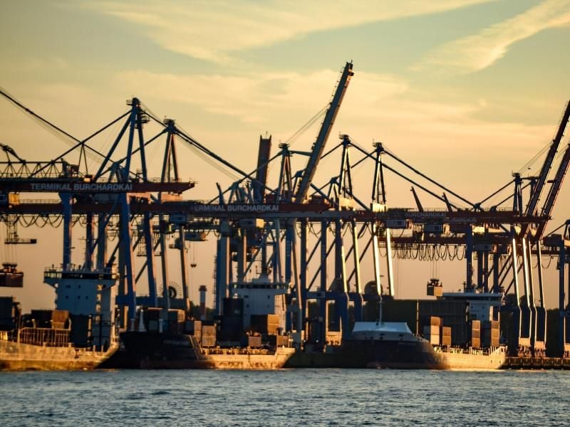 Containerschiffe werden im Hafen bei untergehender Sonne abgefertigt. Foto: Axel Heimken/Archiv