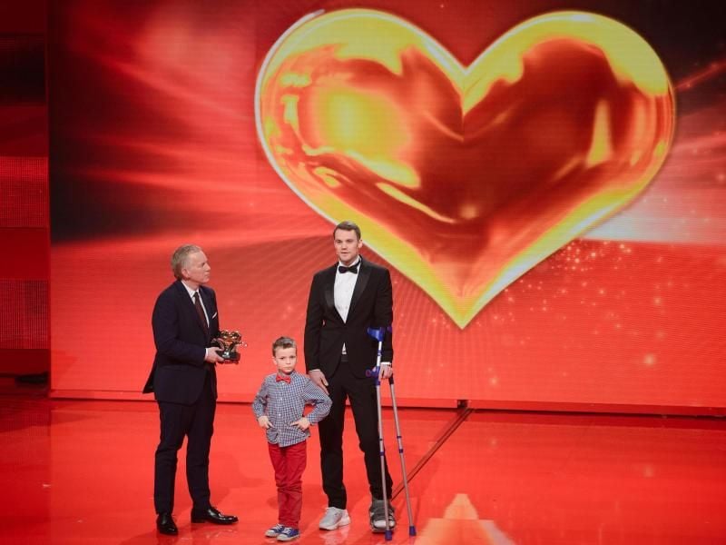 Der kleine Frederik und Johannes B. Kerner übergeben Manuel Neuer das „Goldene Herz”. Foto: Gregor Fischer